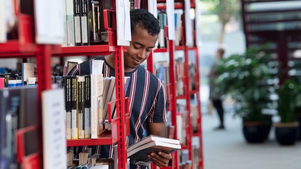 Person kigger på en bog på et bibliotek. 